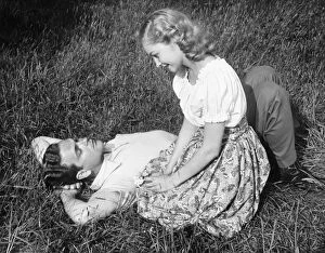 Young couple resting on lawn, (B&W)