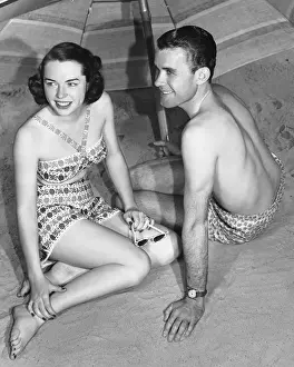 Swimming Trunks Prints: Young couple sitting under beach umbrella