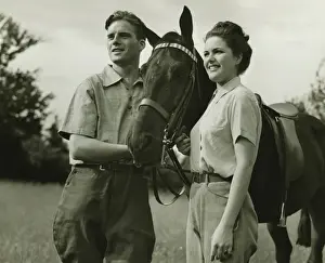 Reins Prints: Young couple standing with horse in field, (B&W)