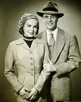 Young couple in studio, man holding woman, smiling, (B&W), portrait