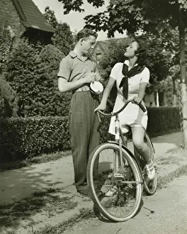 Suburbs Prints: Young couple talking on street, woman on bicycle, (B&W)