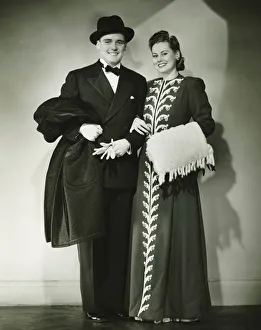 Arm In Arm Gallery: Young couple wearing formal dress standing in studio, (B&W)