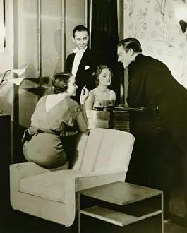 Two young couples gathered around piano in living room, (B&W)