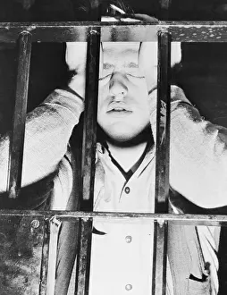 Young Eugene Ratajczak Standing Behind Jail Cell Bars