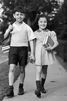 Young girl & boy walking to school w / books