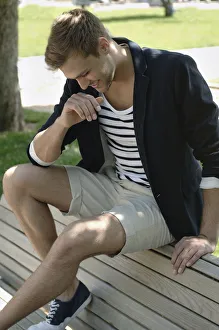 Relax Collection: Young man in casual outfit sitting on a park bench in a park