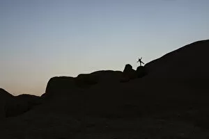 Young man jumping on a granite rock, near Spitzkoppe granite peaks, Damaraland, Namibia, Africa