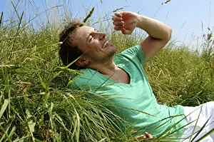 Satisfaction Gallery: Young man lying in tall grass, smiling, sunbathing