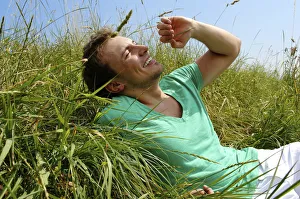 Satisfaction Gallery: Young man lying in tall grass, smiling, sunbathing
