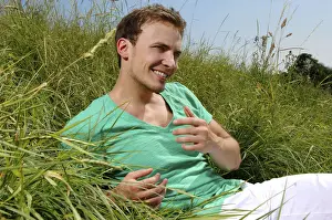 Pause Prints: Young man lying in tall grass, smiling, sunbathing