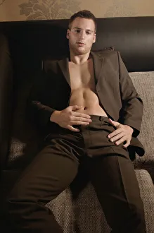 Casual Collection: Young man in a suit and without shirt lying on a couch