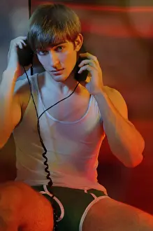 Young man in underwear with headphones in colorful light