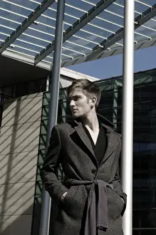 Shorthaired Prints: Young man wearing an overcoat in front of modern architecture, fashion shoot