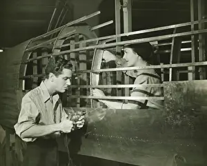 Focused Prints: Young man and woman working in plane body in factory, (B&W)
