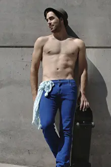 Athleticism Prints: Young shirtless skater in front of a concrete wall