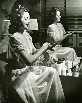 Interior Space Prints: Young woman applying cream in front of mirror, (B&W)