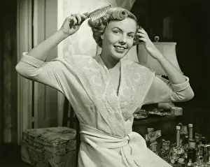 Brushing Prints: Young woman brushing hair, at home, (B&W), portrait
