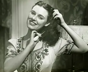 Young woman combing hair, (B&W), portrait