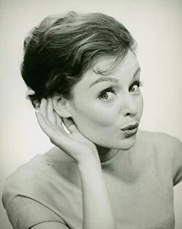 Young woman cupping hand to ear, (B&W), (Portrait)