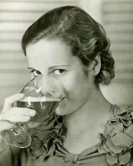 Young woman drinking glass of beer, (B&W), portrait