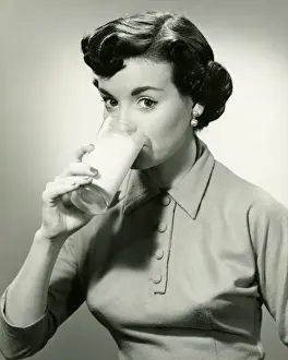 Young woman drinking glass of milk, (B&W), portrait