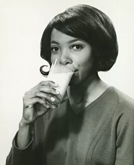 Images Dated 5th May 2006: Young woman drinking milk in studio, smiling, (B&W), portrait