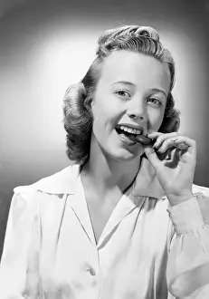 Snack Prints: Young woman eating chocolate, portrait