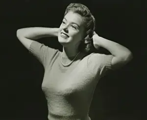Jumper Prints: Young woman with hands behind head in studio, (B&W), close-up