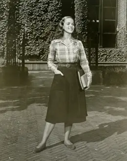 Young woman holding books, standing outdoors
