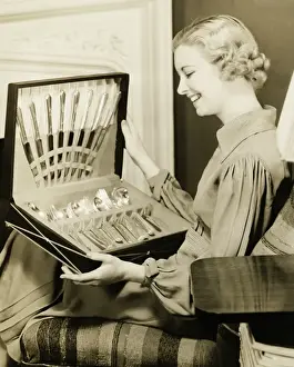 Cutlery Prints: Young woman holding open box with cutlery, smiling, (B&W)
