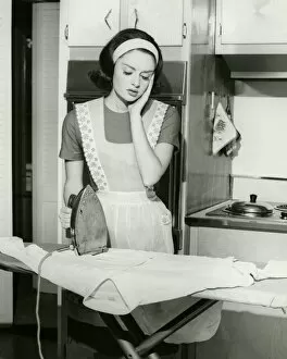 Board Gallery: Young woman ironing in kitchen, (B&W)