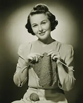 Knitting Needle Prints: Young woman knitting in studio, (B&W), portrait