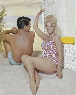 1962 Prints: Young woman leaning on swing chair beside man, smiling