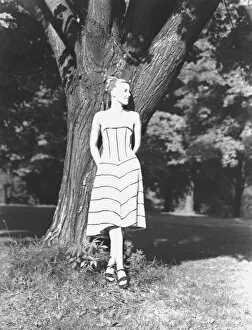 Young woman leaning on tree in park, (B&W)