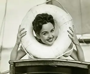 Permed Hair Prints: Young woman looking through lifebelt, smiling, (B&W)