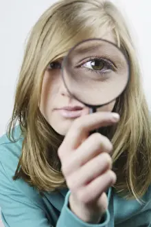 Eyeglasses Prints: Young woman with magnifying glass in front of her eye