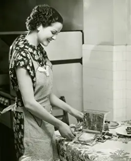 Chores Prints: Young woman making slice of toast, (B&W), portrait