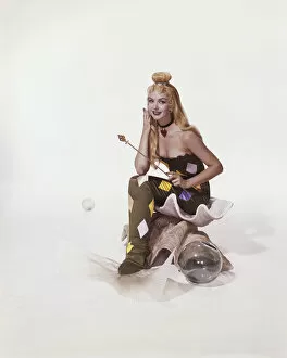 Magic Wand Gallery: Young woman in mermaid costume sitting on shell, smiling, portrait