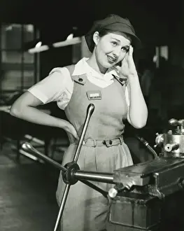 Overalls Prints: Young woman in overalls standing by lathe in factory, (B&W)