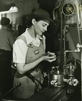 Bib Overalls Gallery: Young woman in overalls working by lathe in factory, (B&W)