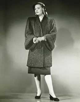Curls Prints: Young woman in Persian lamb coat standing in studio, (B&W)