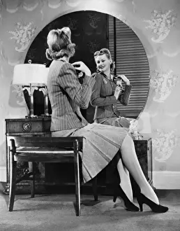 Wall Paper Prints: Young woman pinning artificial flowers to jacket in front of mirror (B&W)