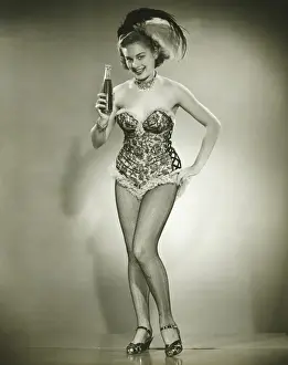 Young woman posing in studio, showing bottle with beverage, (B&W)