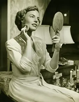 Young woman powdering face, at home, (B&W), close-up
