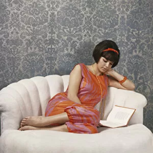 Images Dated 18th July 2011: Young woman reading book on sofa