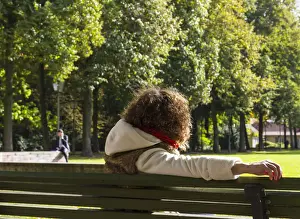 Park Man Made Space Prints: Young woman sitting on a bench watching a man speaking on the phone