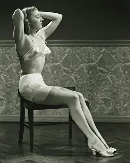 Blonde Hair Prints: Young woman sitting on chair, holding hands on head, (B&W)