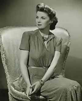 Poise Prints: Young woman sitting on chair indoors, (B&W)