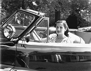 Driver Gallery: Young woman sitting in convertible car, (B&W), portrait