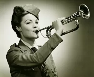 Young woman in soldiers uniform playing on trumpet, (B&W), portrait
